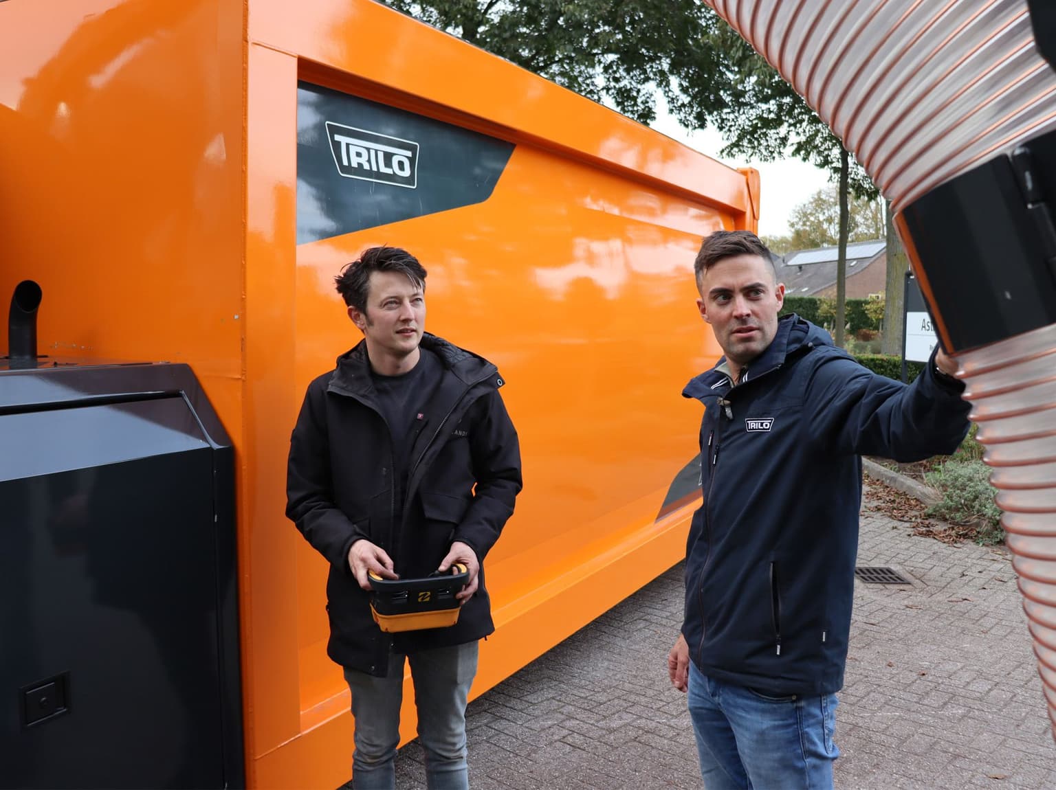 Trilo TX Vacuum Container bei einer Projektübergabe, während Mitarbeitende technische Details der Maschine besprechen.